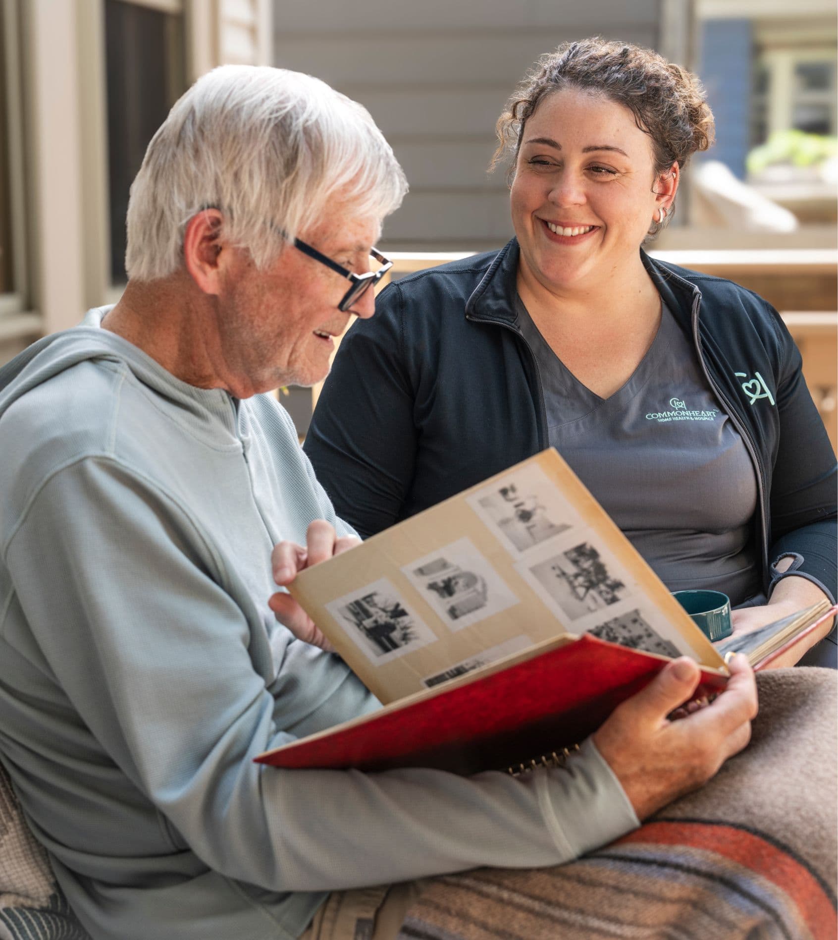 A Commonheart Hospice nurse sitting with a patient who is looking through old photos